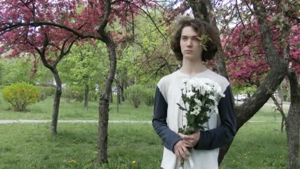 Przystojny facet czeka na swoją dziewczyną w różowy wiosna park, 4k, Ultrahd, Uhd — Wideo stockowe