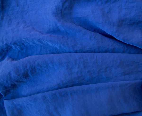Luxuriöser teurer blauer Stoff als eleganter Hintergrund mit schönen Lichttönen. Weiche Falten fallen und erzeugen Lichtwellen — Stockfoto