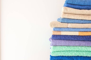 Bir sürü renkli banyo havlusu üst üste yığılmış. Oteller, ev, banyo, mutfak için izole edilmiş pamuk havlular.
