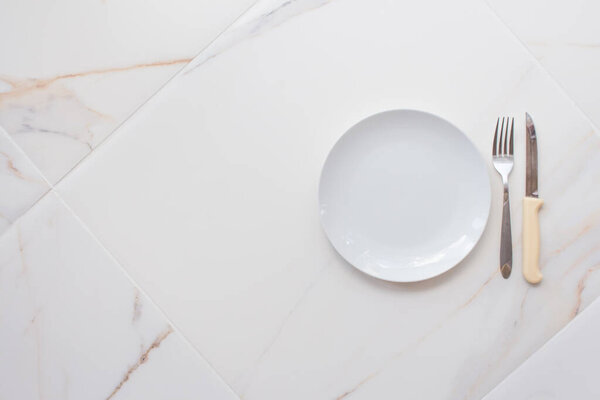 Пустой керамической пластины изолированы на белом мраморном фоне. Принято. Концепция рецепта меню