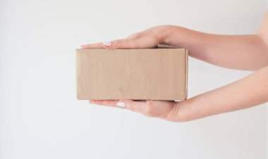 Kadın ellerinde bir paket olan karton kutu. Salgında eve güvenli teslimat kavramı. Uzayı kopyala Online bir mağazadan sipariş geldi.