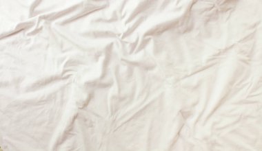 Düz beyaz arka plan. Kumaş dokusu ve pamuk kumaş kıvrımlarıyla modern minimal arkaplan. Üst görünüm. 