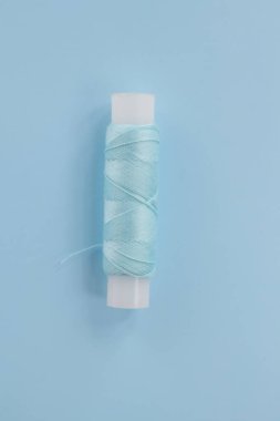 Üretim konsepti. Kıyafet tamiri, mevsim için yeni bir koleksiyon dikmek. Mavi arka planda beyaz iplik makarası. En küçük üst görünüm.