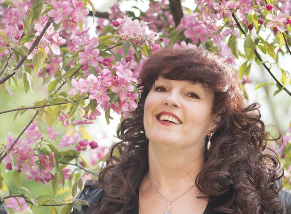 Outdoor portrait of the middle age woman beside a blossoming app — Stock Photo, Image