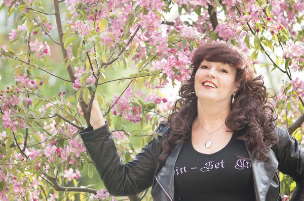 Outdoor portrait of the middle age woman beside a blossoming app — Stock Photo, Image