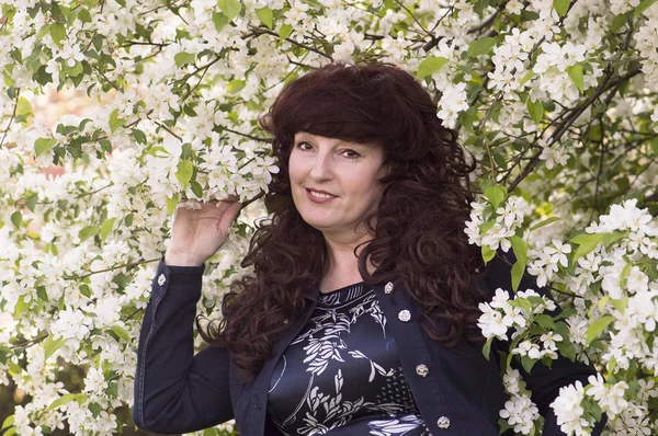 Retrato al aire libre de la mujer de mediana edad junto a una aplicación en flor — Foto de Stock