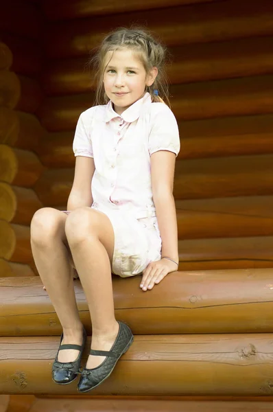 Het meisje is sittind op een logboek. — Stockfoto