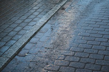 Akşam yağmurunda su birikintileri olan gri kaldırım taşları. Islak taşlar..