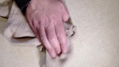 Adam evi temizliyor. Elle masadaki kiri bir bezle temizliyor. Üst görünüm.