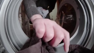 Çamaşır yıkayan adam. Kirli çamaşırları çamaşır makinesine koyuyor..