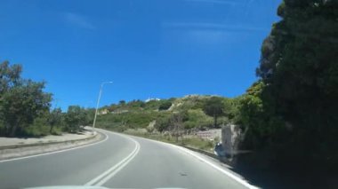 Yunanistan 'da mavi gökyüzünün altındaki dağlarda otoyolda araba sürüyor. POV