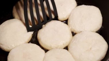 Elinde spatula olan bir el, tavada yağda kızartılmış krep çevirir. Dökme demir tavada krep..