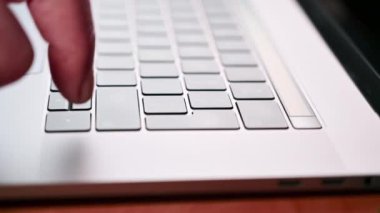 Bir adamın eli dizüstü bilgisayardaki giriş tuşuna birden fazla kez basar. Evde ya da ofiste çalış..