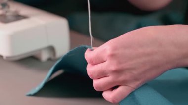 Ev hanımı elleri yeşil kumaşı temizliyor. Evde giysi tamiri.