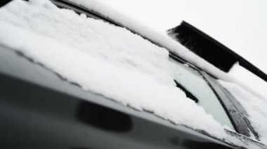 Adam arabanın camından kar temizliyor. Ulaşım, kış, hava, insanlar ve araba kavramı.