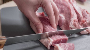 Kesme tahtasında çiğ et kesiyorum. Bıçak ve domuz etiyle yakın plan çekimler..