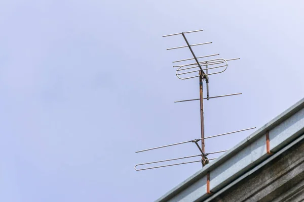Metal TV antenna on the roof against the clear blue sky. TV aerial.