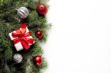 Beyaz arka planda Noel kompozisyonu. Beyaz hediye kutuları, içinde köknar dalları ve oyuncaklar olan kırmızı kurdele var. Tebrik etmek için fotokopi alanının üstünü göster