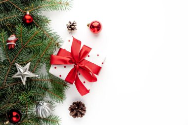 Arkaplanda hediye kutusuyla Noel kompozisyonu, köknar dallarıyla kırmızı kurdele, oyuncaklar, tebrik etmek için kopya alanı