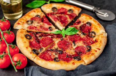 Akdeniz pizzası, salamlı sosis, mozarella, zeytin, Provencal otlar, arka planda imzalı domates sosu.