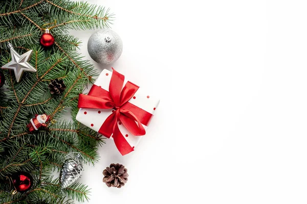 ギフトボックスを背景にクリスマスの組成物 モミの枝 おもちゃ あなたのお祝いのためのコピースペースと赤いリボン — ストック写真
