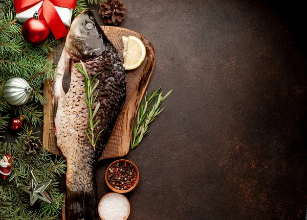 raw carp for preparation for the holiday Christmas on a background of stone with Christmas trees and Christmas decorations