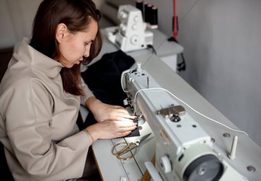 Kız Covid-19 'dan korunmak için dikiş makinesine maske dikiyor. 