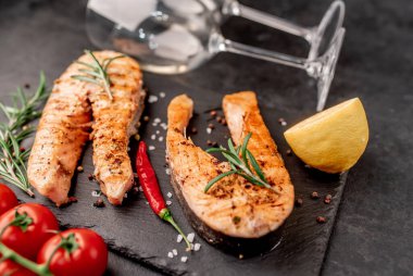 İki kişilik yemek, somon bifteği ve şarap için bardaklar..