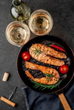 İki kişilik akşam yemeği, somon bifteği ve beyaz şaraplı bardaklar..