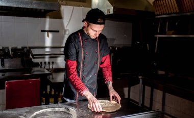 Mutfakta pizza için hamur yapan şefin manzarası, yemek pişirme konsepti.