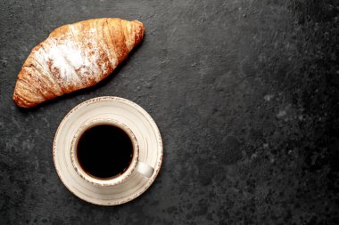 Tahta arka planda kruvasan olan sade kahve. 