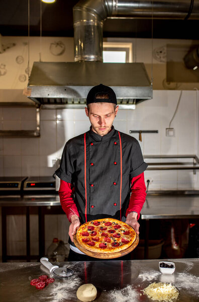 View of chef showing fresh pizza at kitchen, cooking concept