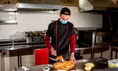 Üniformalı şef restoranda mutfakta yemek pişiriyor.