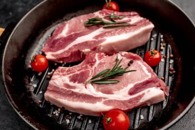 Biberiyeli çiğ et dilimleri ve siyah arka planda baharatlar. 