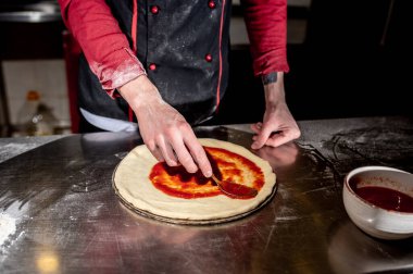 Mutfakta pizza yapan şefe yakın çekim, yemek pişirme konsepti.