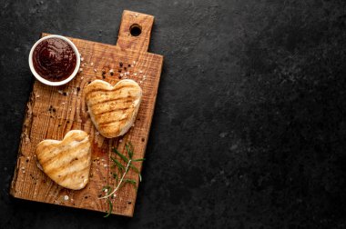 Kalpler şeklinde ızgara tavuk bifteği ve arka planda baharatlar ve otlar. 