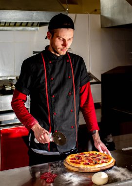 Şefin mutfakta taze pizza kesmesi, yemek pişirme konsepti