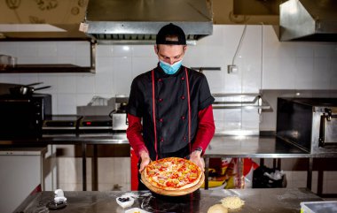 Üniformalı şef restoranda mutfakta yemek pişiriyor.