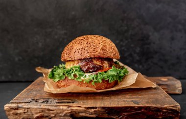 Etli taze sandviç, siyah taş arka planda kızarmış burger.