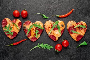 Kalp şeklinde pizza dilimleri siyah taş arka planda