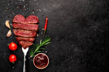 Siyah arka planda baharatlı dilimlenmiş biftek. 