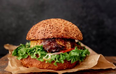 Etli taze sandviç, siyah taş arka planda kızarmış burger.