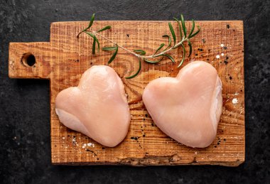 Siyah arka planda baharatlı çiğ tavuk göğsü.