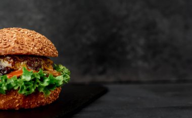 Etli taze sandviç, siyah taş arka planda kızarmış burger.