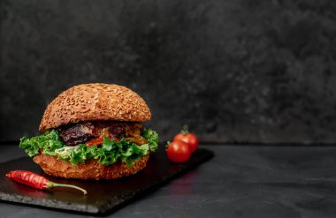 Etli taze sandviç, siyah taş arka planda kızarmış burger.