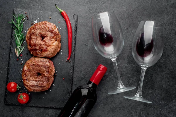 grilled beef steak with wine and spices on black background