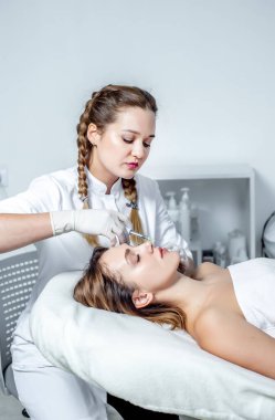 Genç bir kadın güzellik salonunda yüz masajı yaptırıyor.