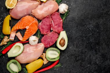 Siyah tahta yüzeyinde meyve ve sebzeli çiğ et ve balık bifteği. 