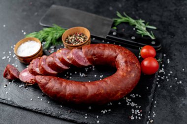 Otlu salam, tuz ve baharat ile siyah arkaplan üzerinde bıçak ile