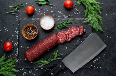 Baharatlar, otlar ve domateslerle servis edilen taze salam.